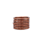 Pila de pulseras lisas color cobre sobre fondo blanco.
