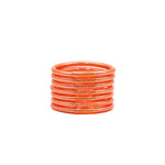 Pulseras naranjas con detalles brillantes apiladas sobre fondo blanco.