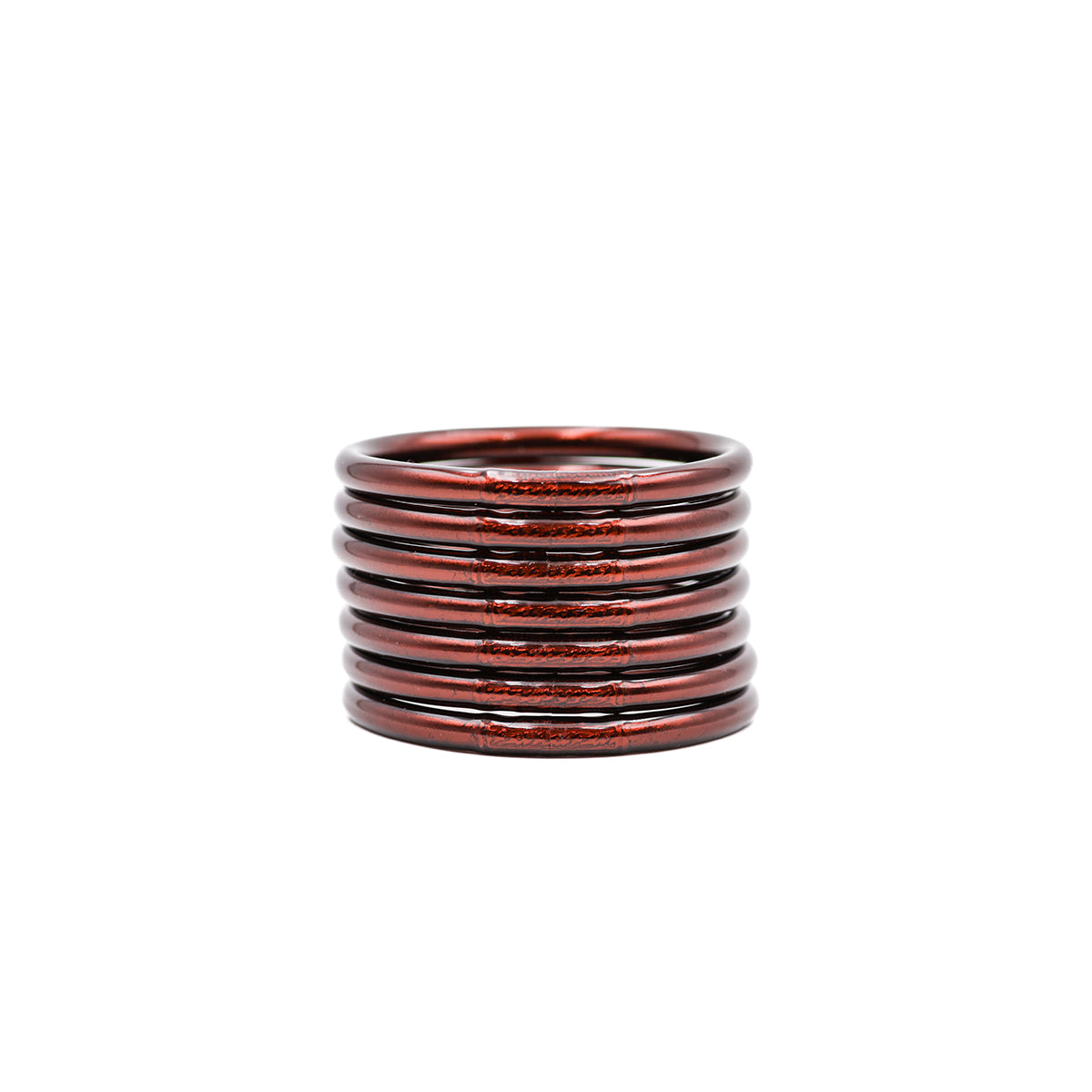 Pulseras en tonos cobre y oscuro apiladas sobre fondo blanco.