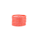 Pulseras naranjas con detalles brillantes apiladas sobre fondo blanco.
