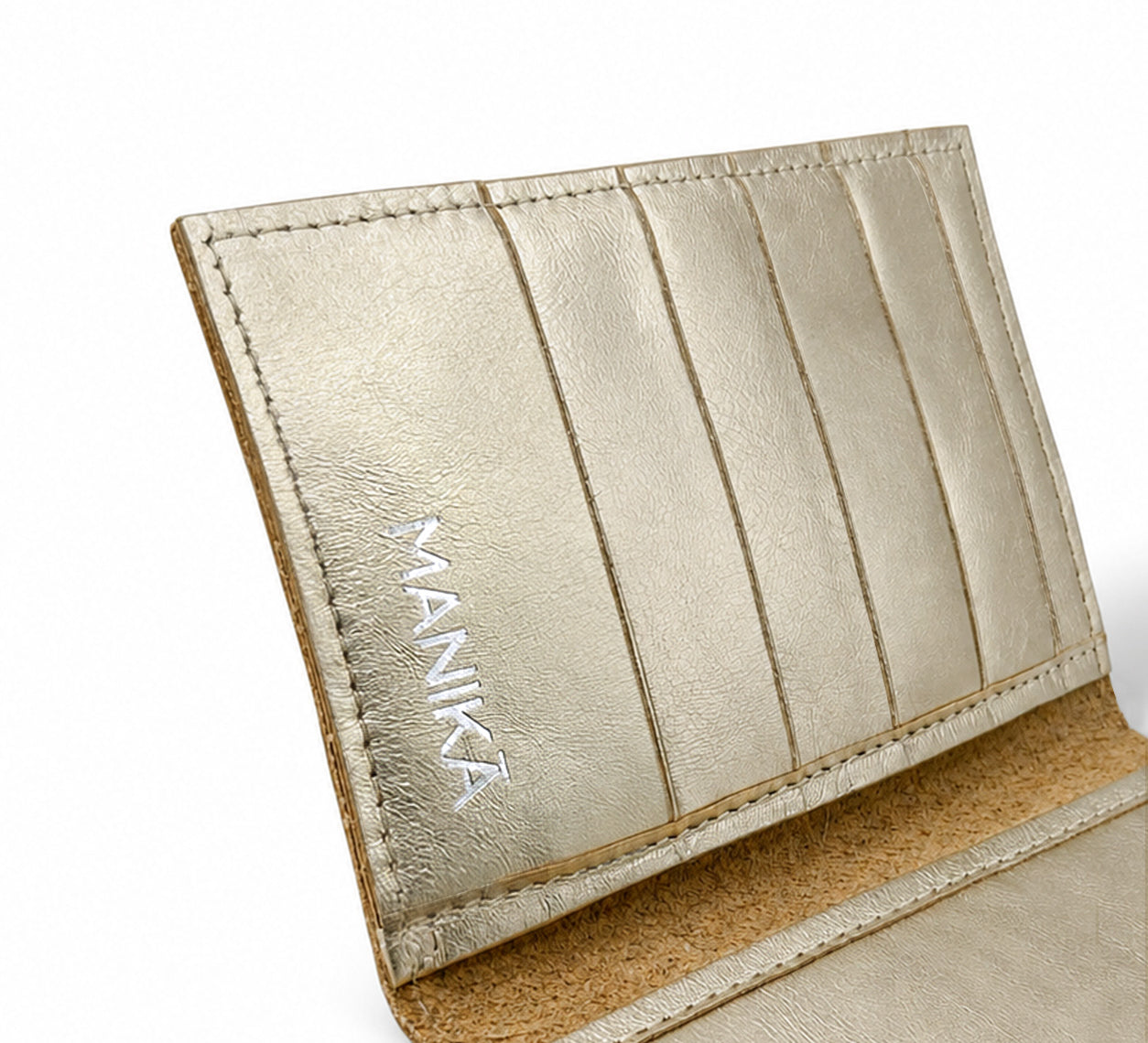 Detalle de los tarjeteros y el logo MANIKĀ grabado en una cartera de piel vacuna metalizada dorada