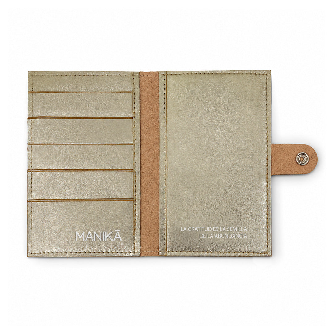 Cartera MANIKĀ de piel vacuna metalizada dorada cerrada con broche metálico, vista frontal sobre fondo blanco